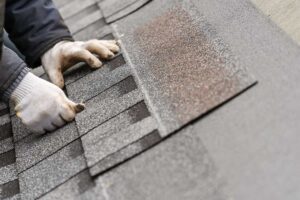 Homeowner inspecting gutters and roof edges beside a snow-ready house in autumn.
